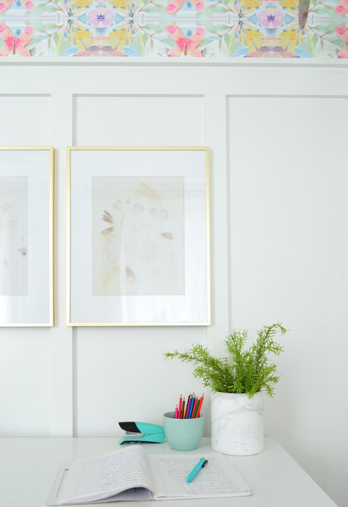 Desk With Gold Frames Hung On White Board And Batten