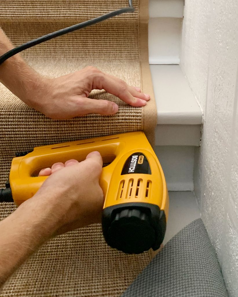 Yellow Electric Stapler Attaching Runner Under Lip Of Stair Tread