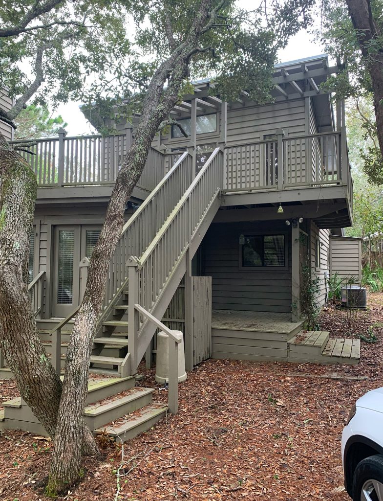 Before Photo of Side Of House With Staircase To Upstairs Porch And Painted Brown