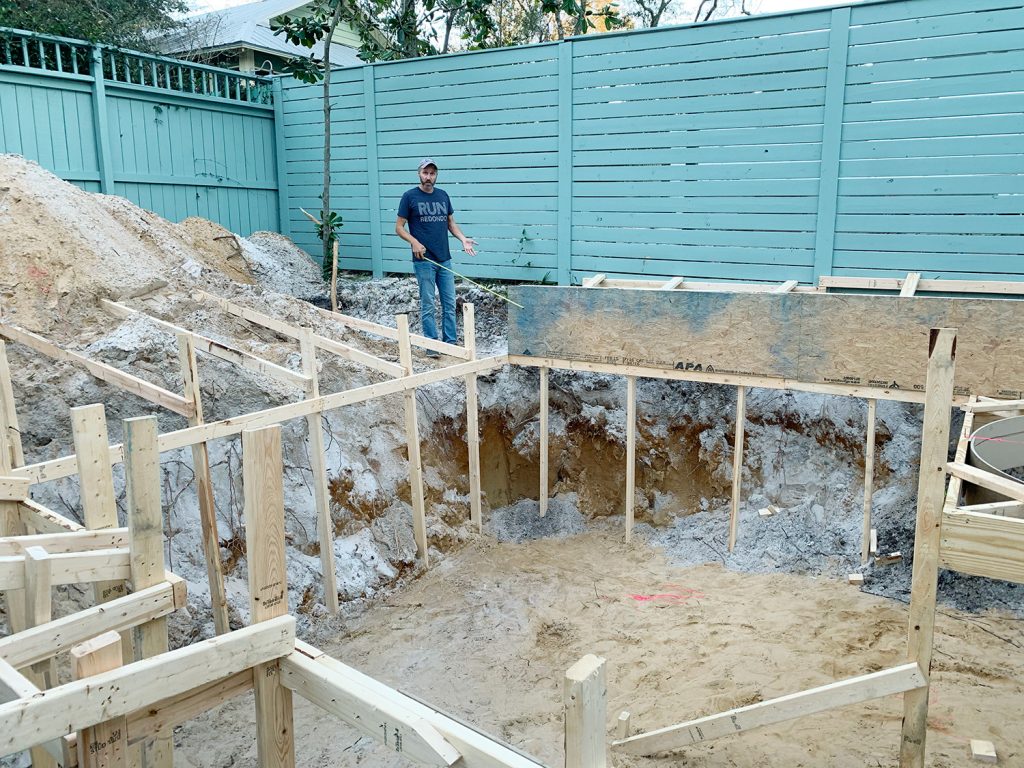 Pool hole framed out with wood and John in background with measuring tape