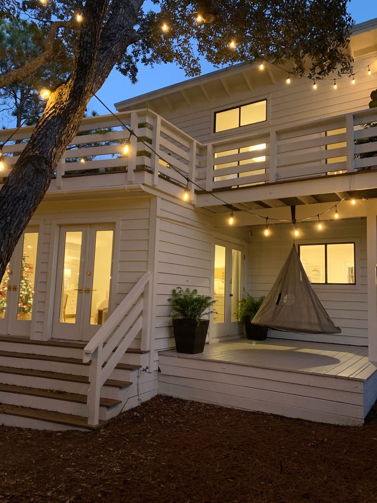 Exterior of white house at night with hanging tent swing on covered side porch